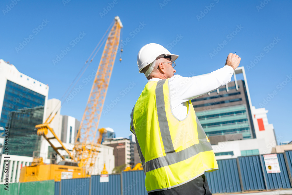 Senior foreman in glasses doing his job at building area on sunny day