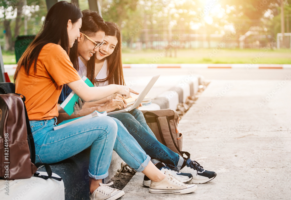 一群年轻或十几岁的亚洲学生在大学里微笑着读着书，看着ta