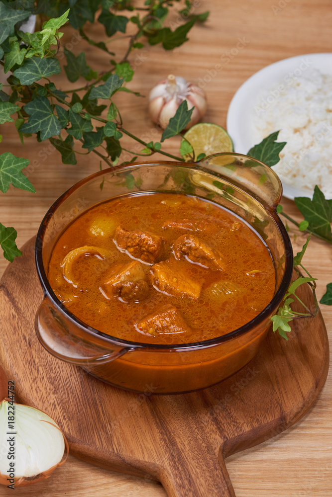 Tasty dinner with chicken curry in bowl on wooden background