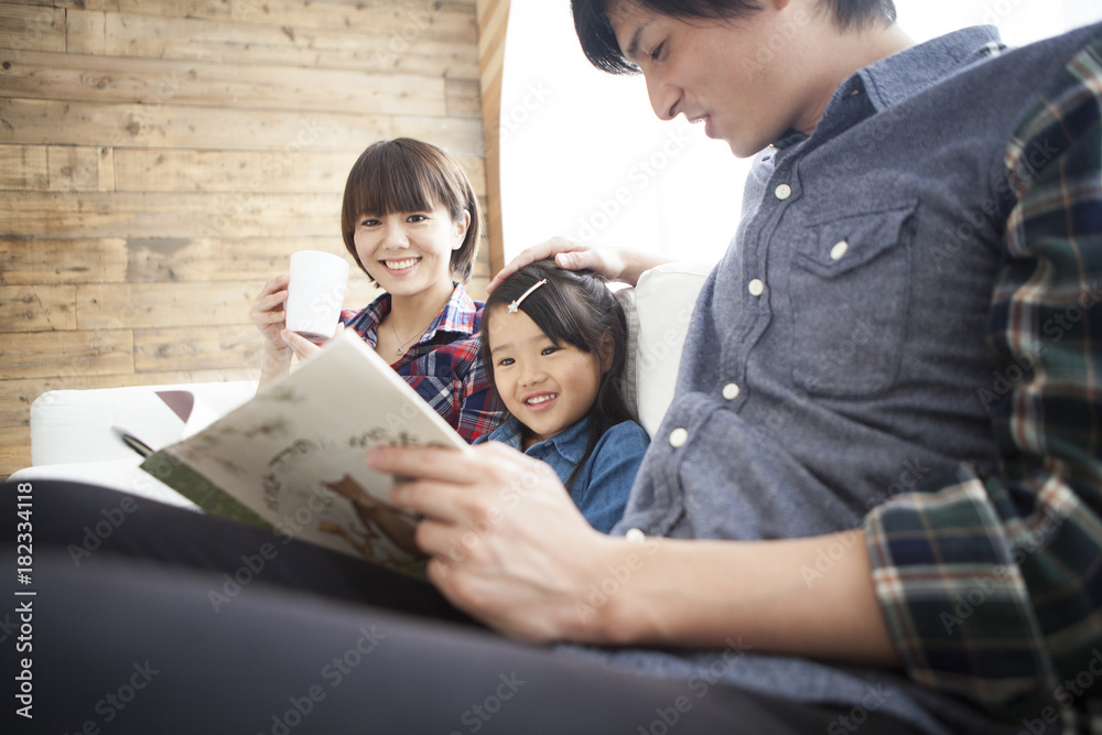 Dad and mommy are reading picture books for their daughter.