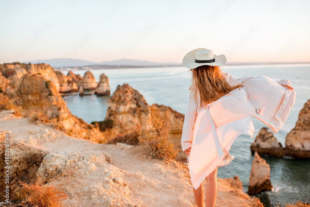 波图加南部拉各斯日出时，一名女子在岩石海岸线上欣赏美景