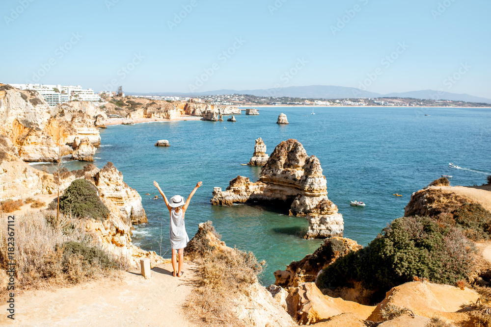 Woman enjoying great view on the rocky coastline during the sunrise in Lagos on the south of Portuga