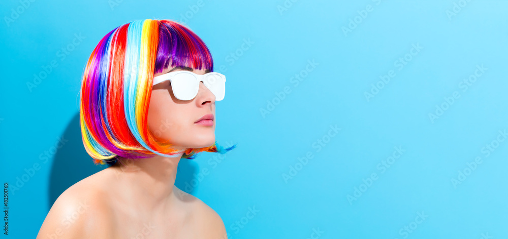 Beautiful woman in a colorful wig on a blue background