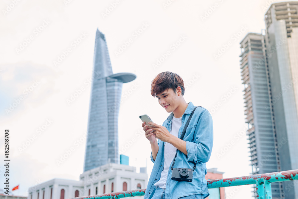 Young asian man tourist using smartphone outdoor in the city