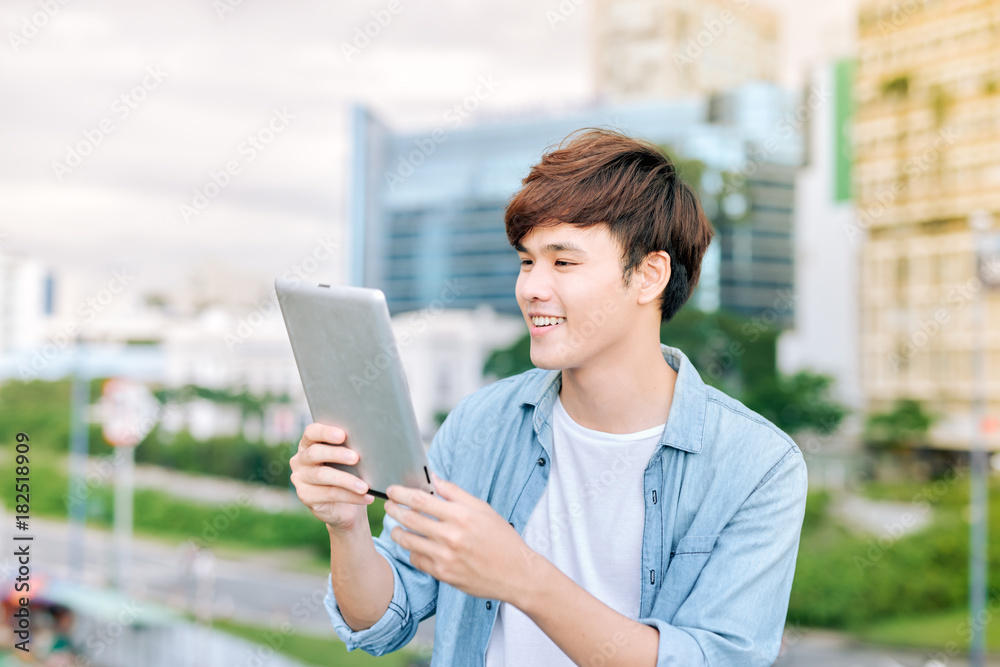 Young asian man tourist using digita; tablet outdoor in the city