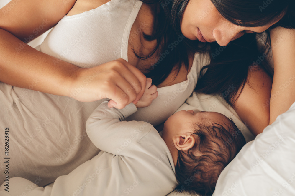 Young woman with a sleeping baby in bed