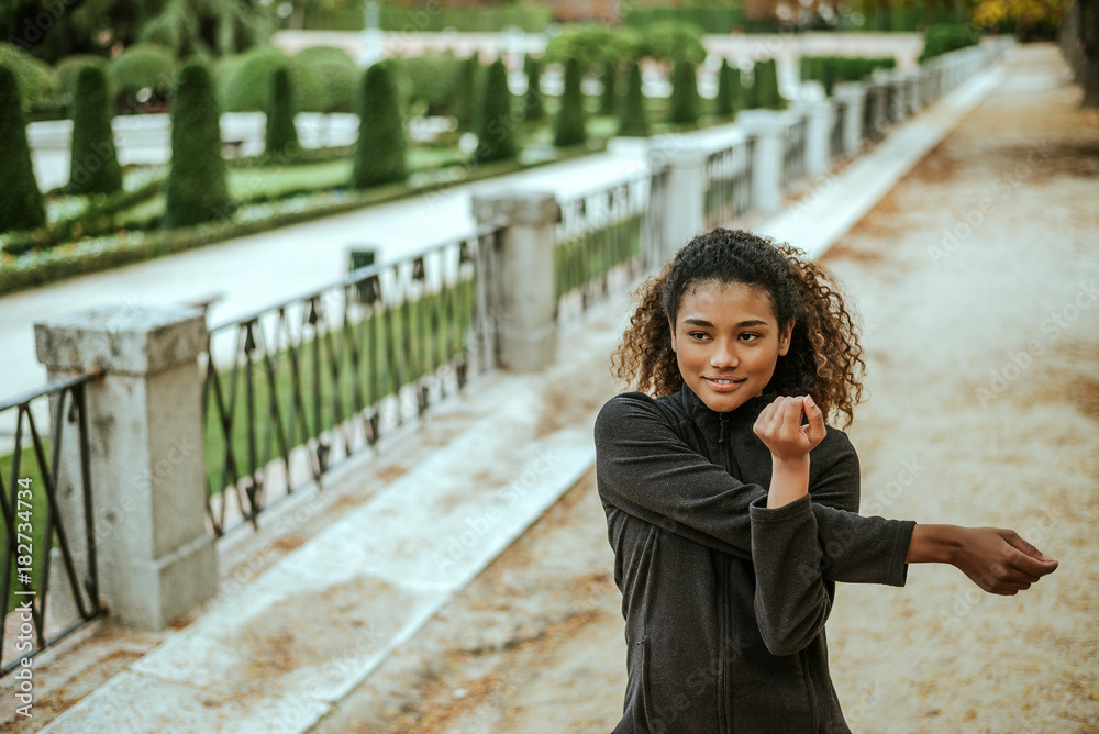 Fit woman stretching her arms outdoors before exercising.