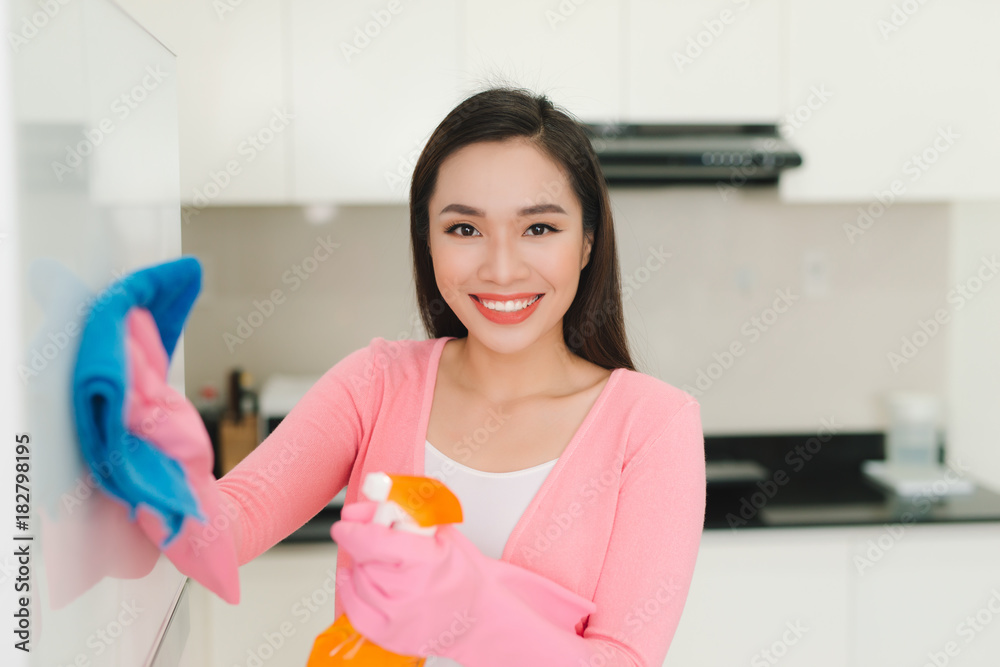 Beautiful asian woman in protective gloves cleaning kitchen cabinet