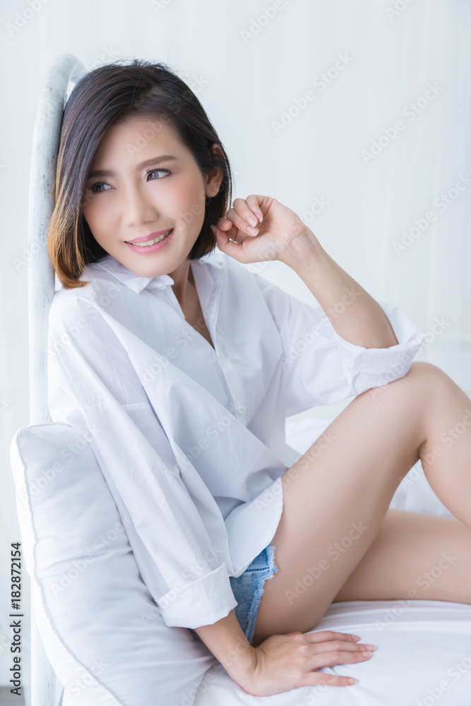 beautiful asian girl white white shirt ralax on white bed next to window curtian with sunlight beaut