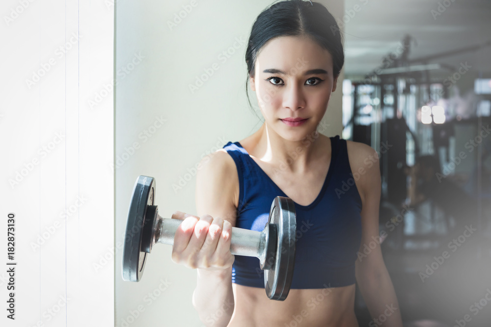 asian strong woman fit and firm healthy concept lifting dumbbell at gym