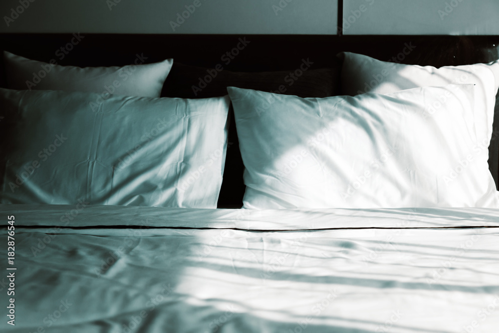 Bed maid-up with clean white pillows and bed sheets in beauty room. Close-up. Lens flair in sunlight