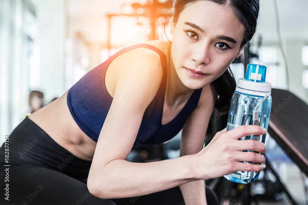 beautiful and smart healthy asian young woman smile while workout at gym fitness center with blur ba