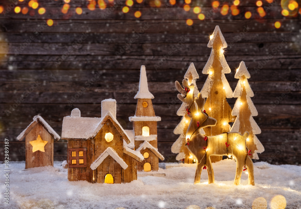 Christmas background with illuminated wooden village and moose