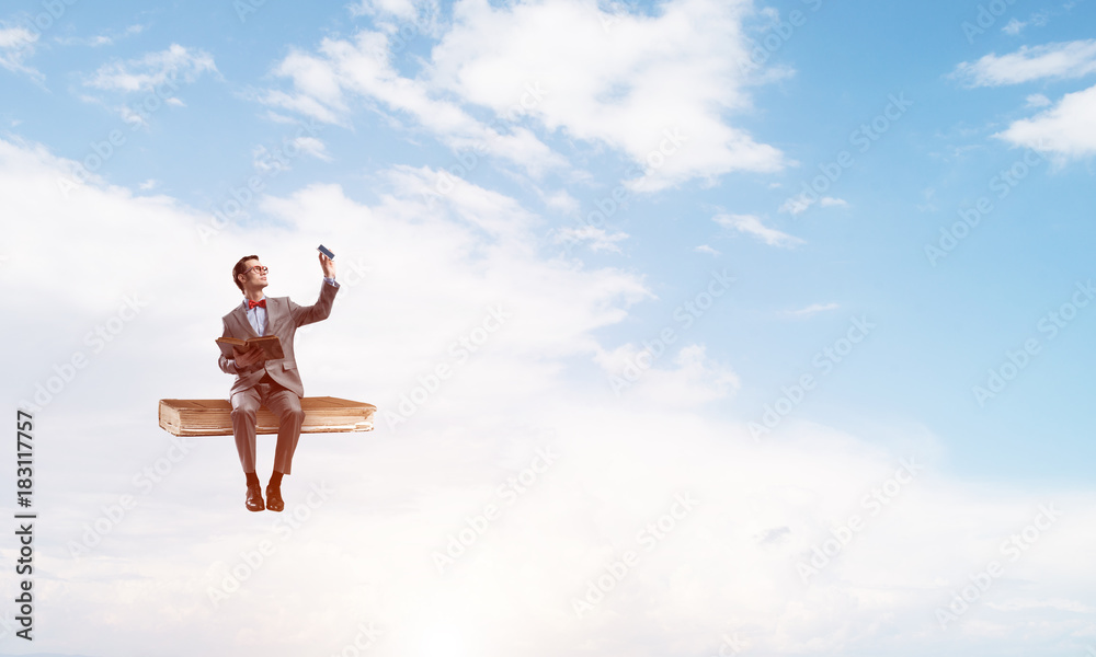 Young businessman or student floating in blue sky and studying the science