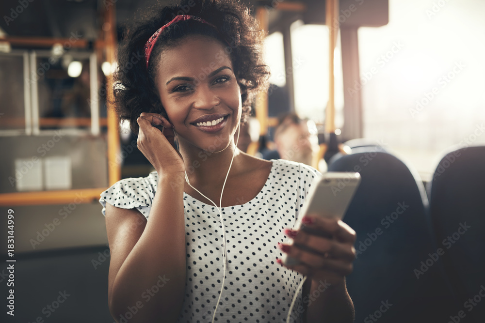 Young African woman standing on a bus listening to music