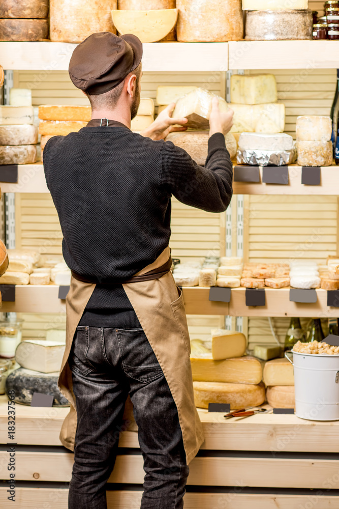 Cheese seller putting goods on the shelves at the cheese store