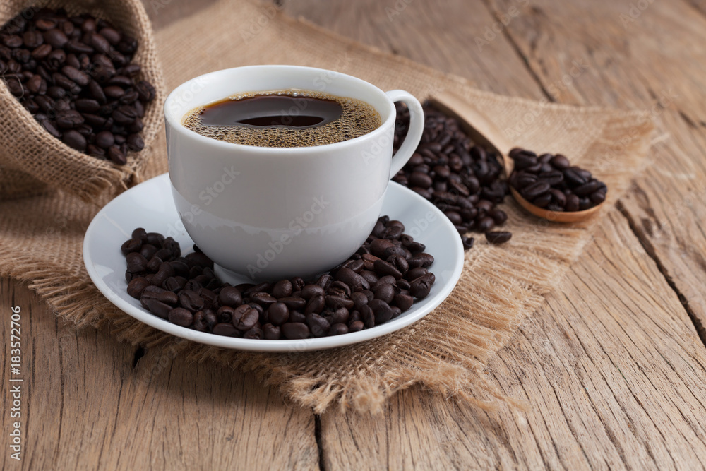 coffee cup and coffee beans on old wood plank background.