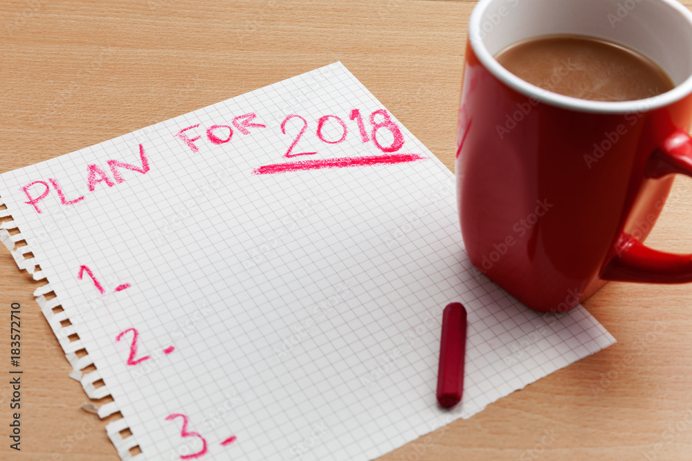 Plan for 2018 text on paper note with coffee cup on business table,business plan and new year backgr