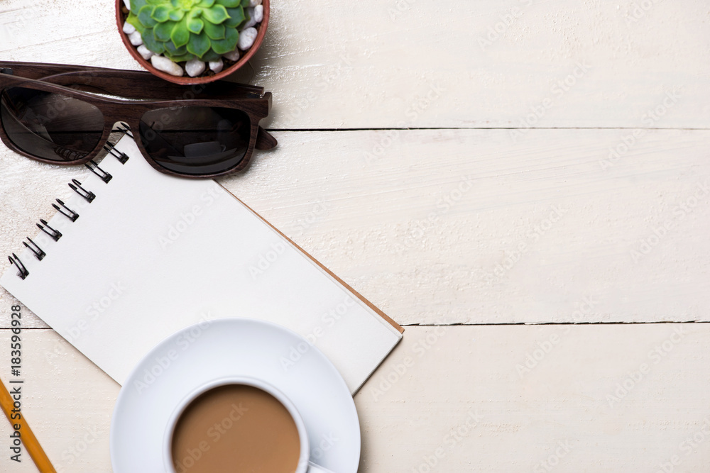 Image of the blank page of small note with pencil, a cup of coffee on wooden background