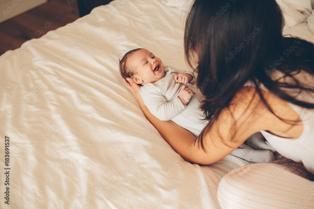 Smiling little boy lying on bed with his mother