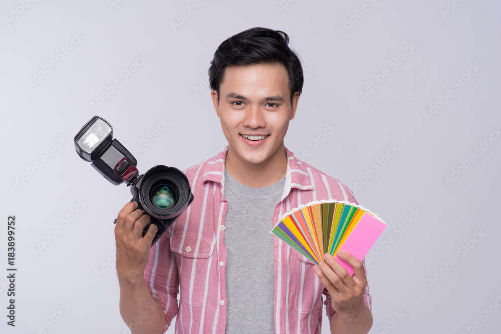 Young asian photographer holding digital camera, while working in studio