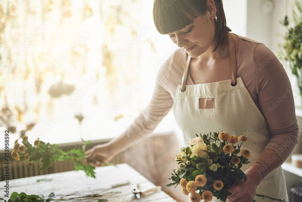 Smiling florist making a bouquet in her flower shop