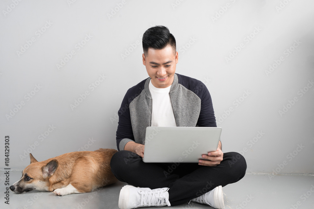 Handsome young businessman is using laptop while sitting with his dog o chair