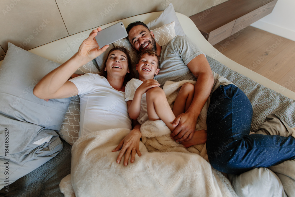 Family taking selfie on bed at home