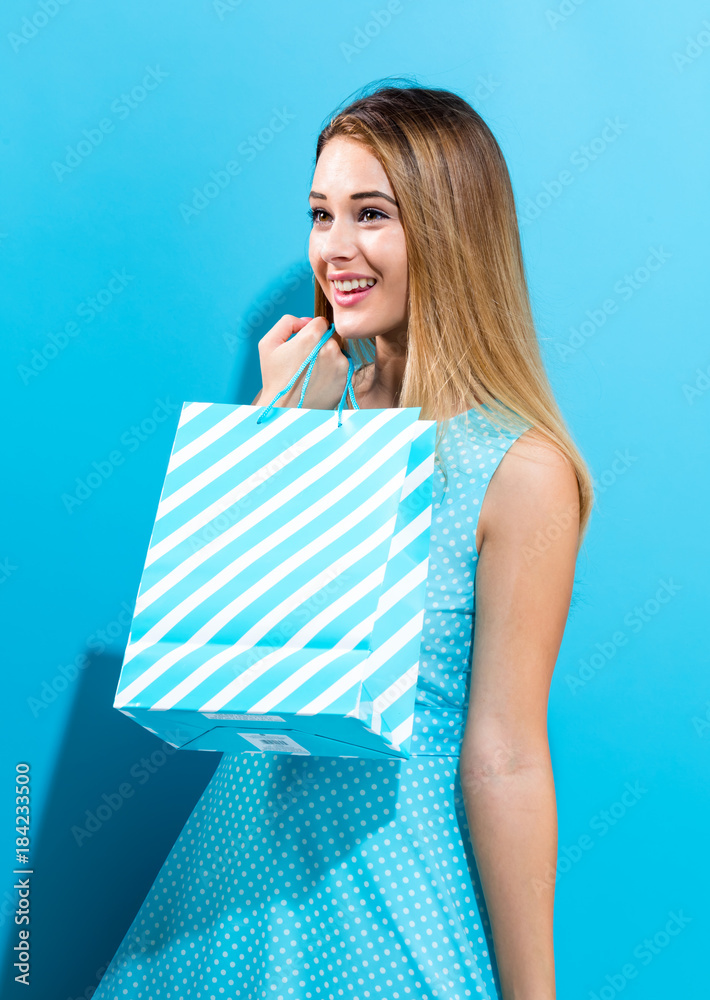 Young woman holding a shopping bag on a blue background