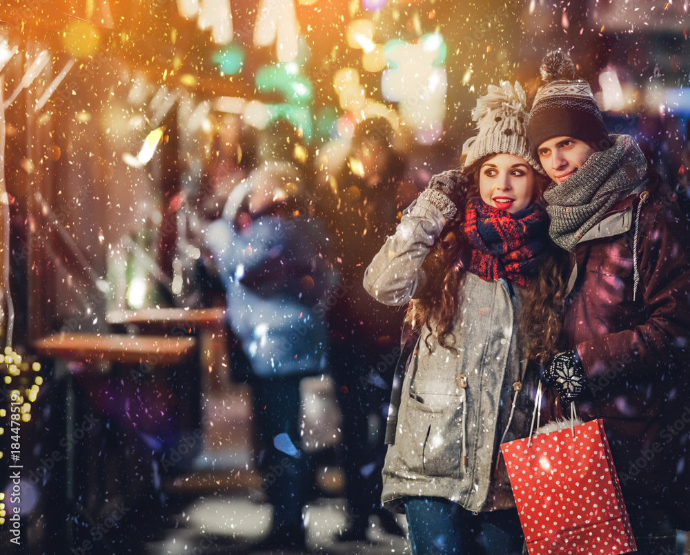 Young couple having fun at fairy Christmas market and buying gifts