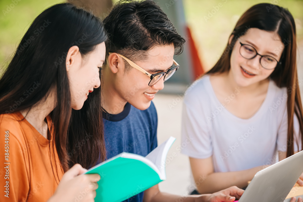 一群年轻或十几岁的亚洲学生在大学里微笑着读着书，看着ta