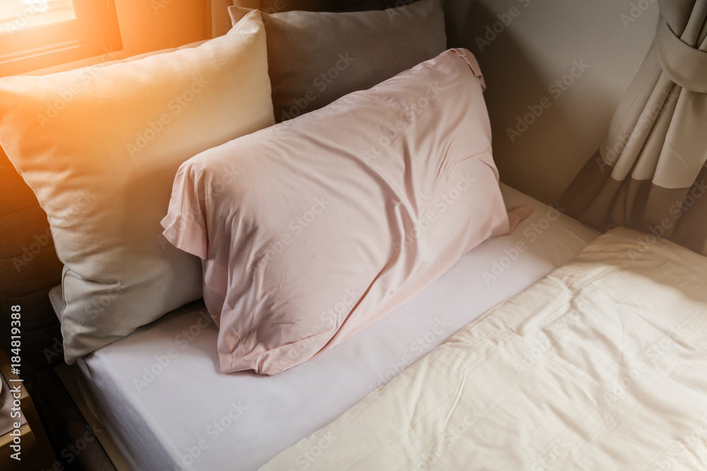 Morning sun light shining through the window to bed and pillows in the bedroom.