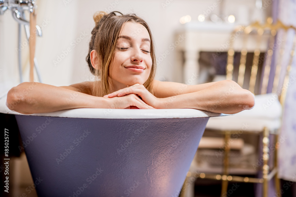 Portrait of a beautiful woman lying in the retro bath in the vintage bathroom