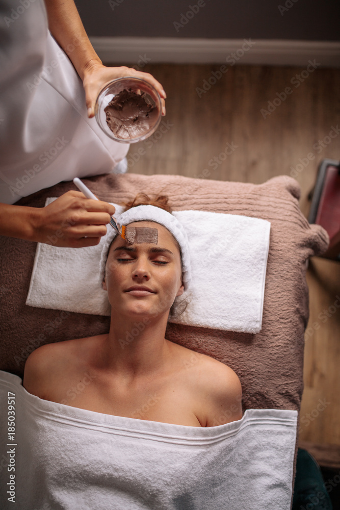 Cosmetician applying facial mask on female face