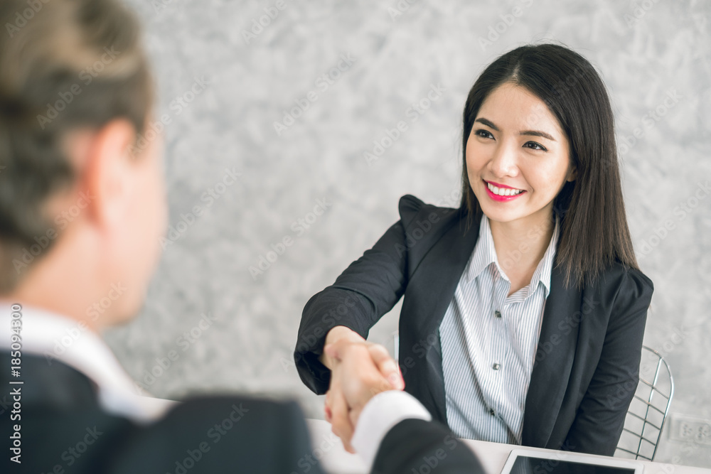 两位商界人士和亚洲商界女性在会议上握手以取得成功并达成一致