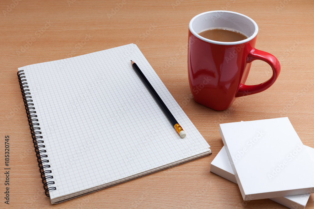 Red coffee cup with white paper note and pencil on business table.