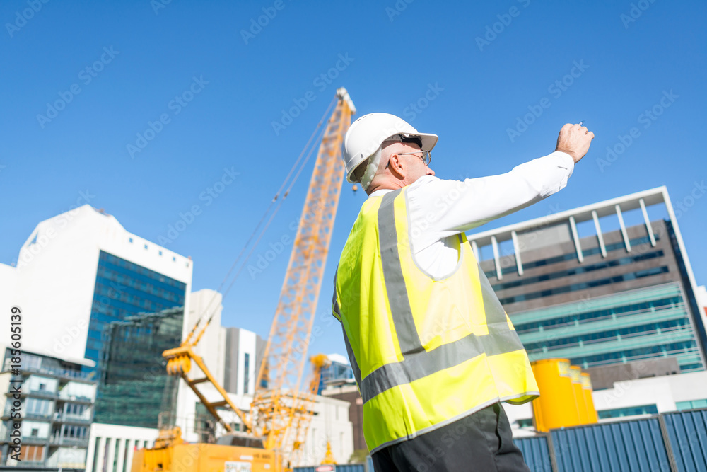 戴眼镜的高级工头在阳光明媚的日子里在建筑区工作