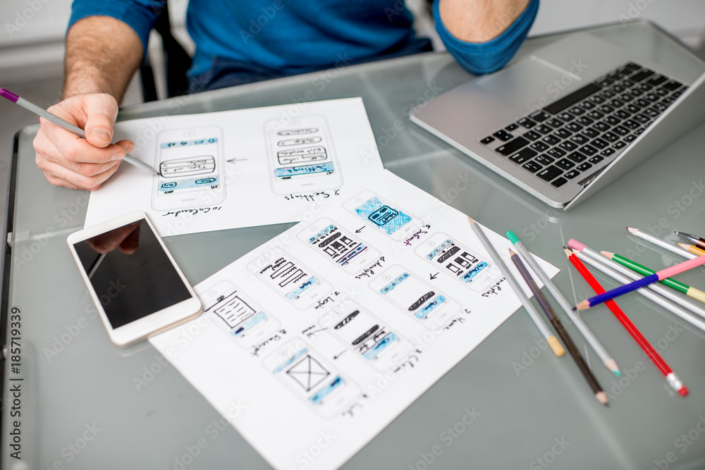 在移动应用程序上工作的用户体验设计师在办公室绘制草图。图片聚焦