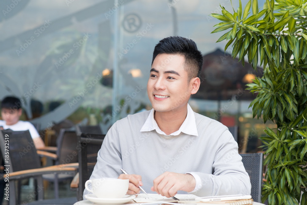 Happy young man working on laptop computer during coffee break in cafe bar