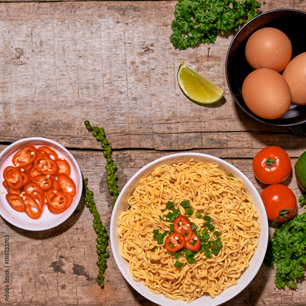 noodle in bowl and ingredients on wood background top view