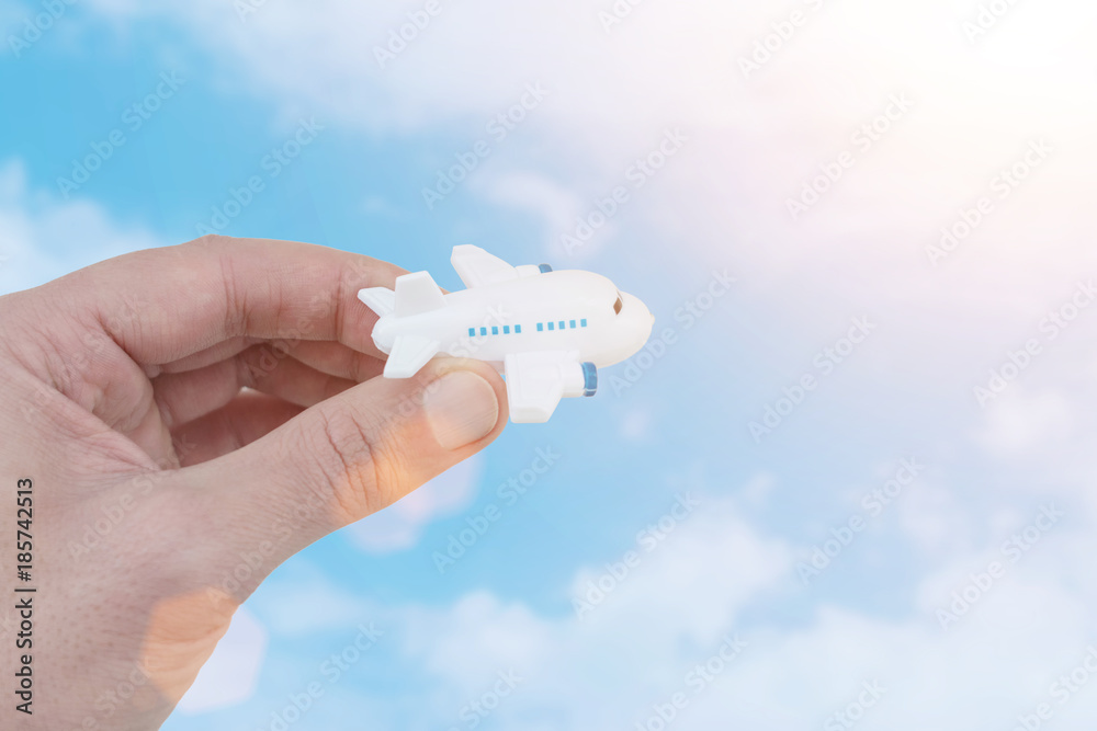 Close-up of hand with toy airplane against cloudy sky.Sunny.