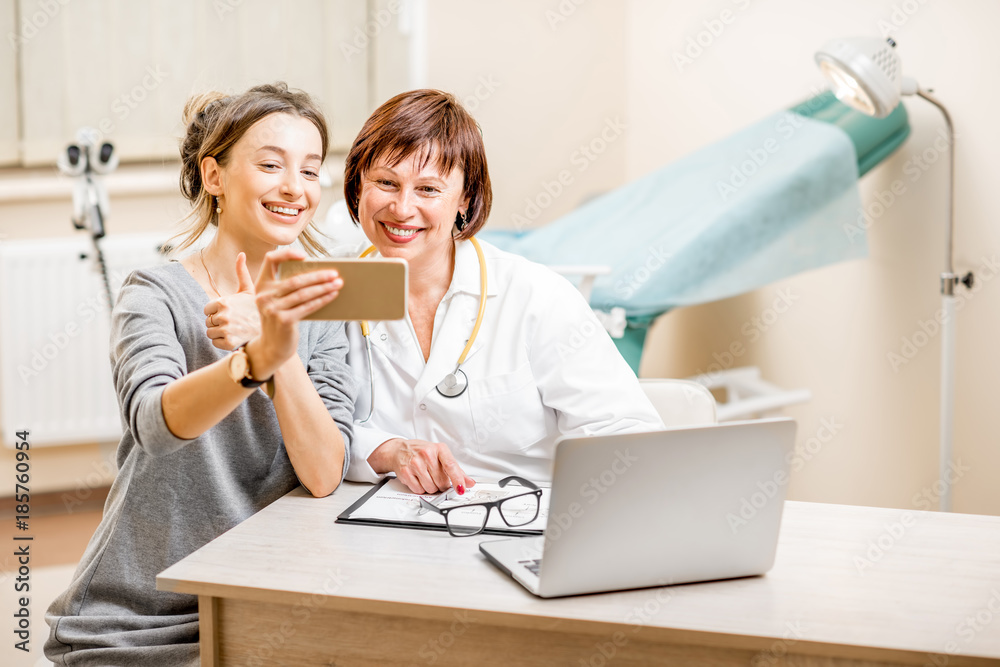 Happy patient and senior doctor making selfie photo sitting in the gynecological office