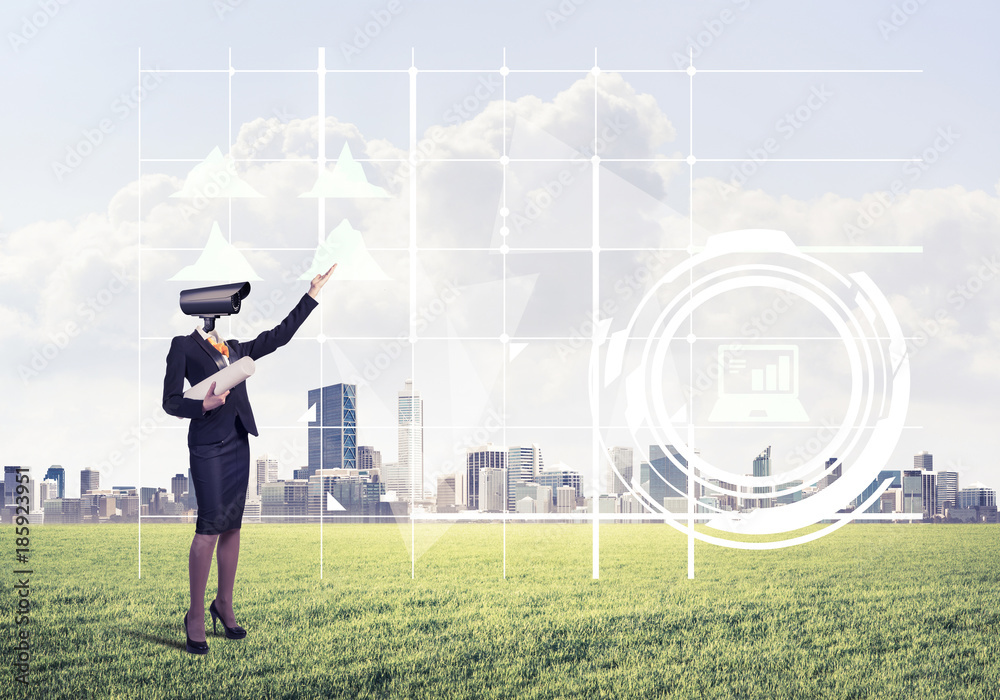 Camera headed woman standing on green grass against modern citys