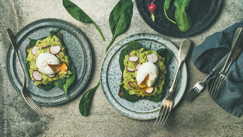 Healthy vegetarian breakfast flat-lay. Whole-grain toasts with avocado, spinach and poached eggs ove