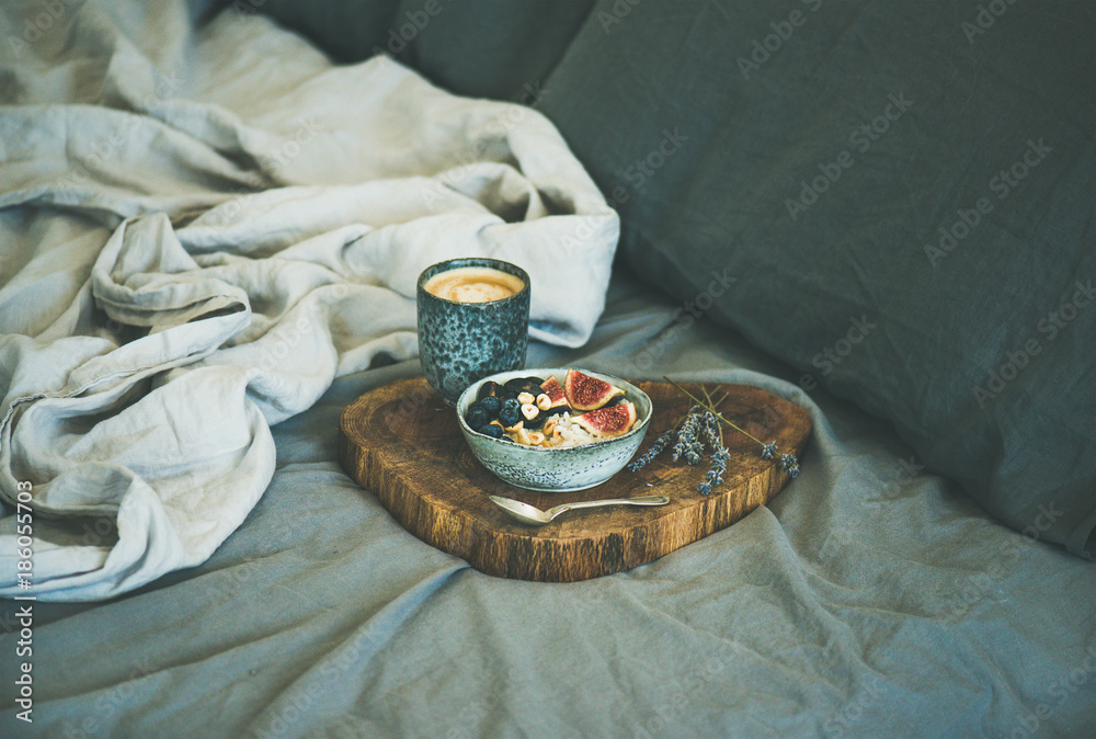 Healthy winter breakfast in bed. Rice coconut porridge with figs, berries and hazelnuts and cup of e