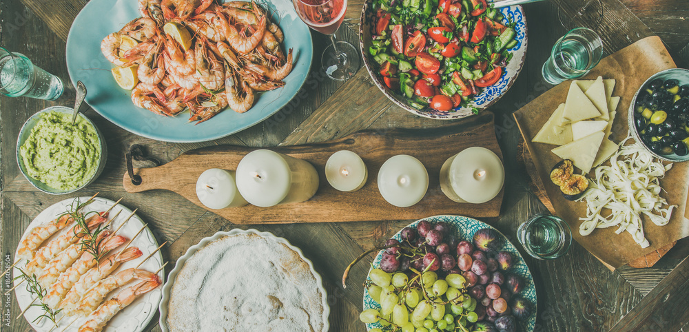 Holiday celebration table setting with snacks. Flat-lay of salad, shrimps, olive, grape, homemade ca