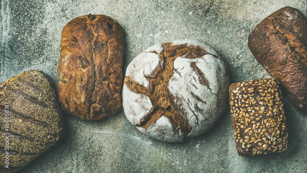 Various bread selection flat-lay. Top view of Rye, wheat and multigrain rustic bread loaves over gre