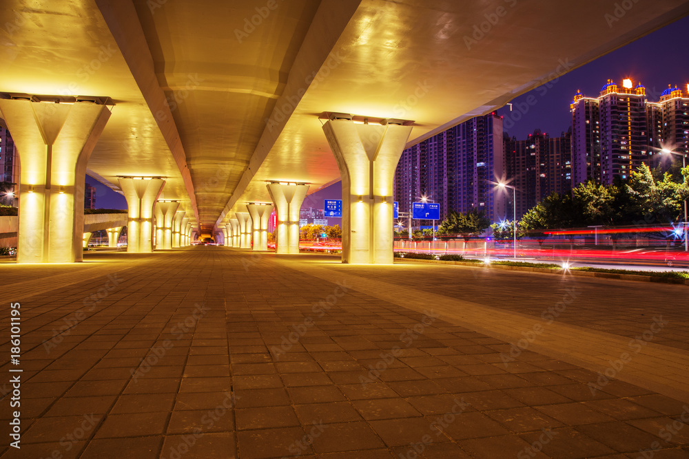 empty sidewalk below elevated road in modern city