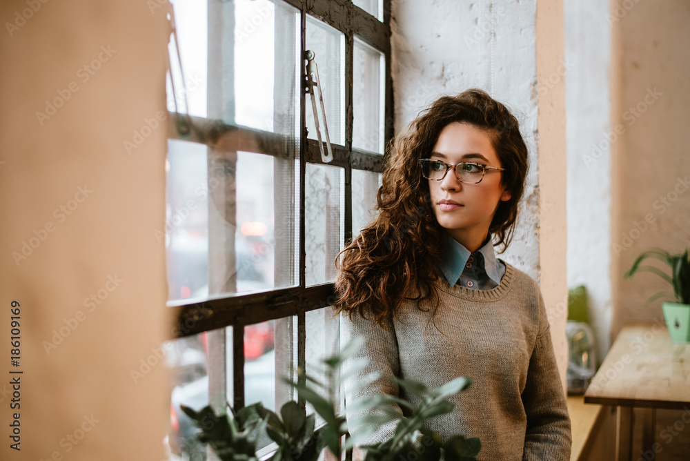 Young woman at home sitting near window relaxing in her living room.