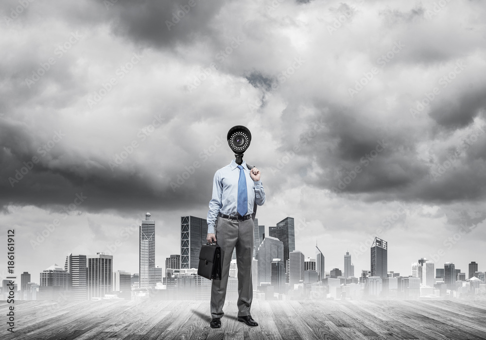 Camera headed man standing on wooden floor against modern citysc